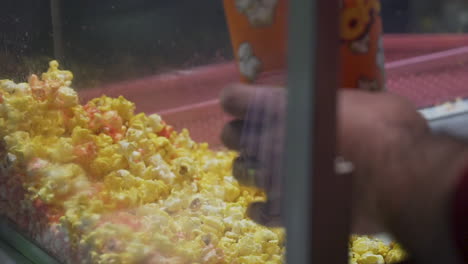 a stationary shot of a man scooping popcorn into a paper cup