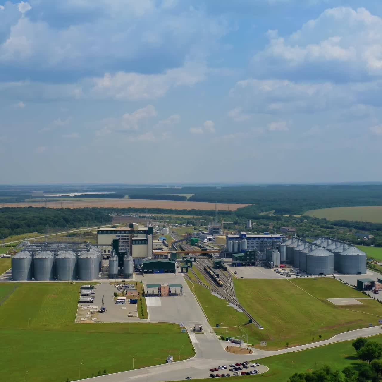 Silver silos on agro plant. Manufacturing plant for processing drying cleaning and storage of agricultural products. Flour, cereals and grain. Granary elevator. Aerial view video
