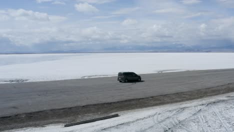 car on road trip through bonneville salt flats in utah - aerial orbit