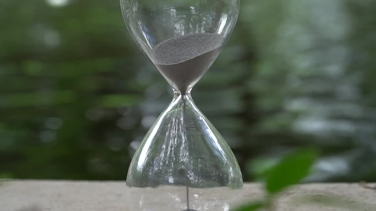 Sand flowing through a hourglass next to a stream