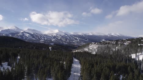 Snowed-Over-Road-in-Silverthorne-Colorado-Forest,-Rocky-Mountains-in-Background