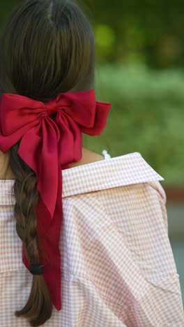 woman with red bow in pink gingham shirt