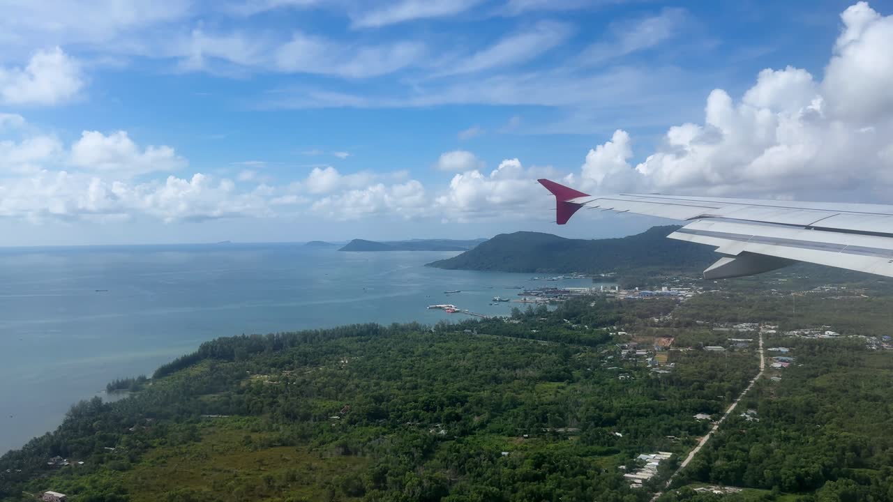 Scenic aerial view of ocean and lush landscape from airplane wing
