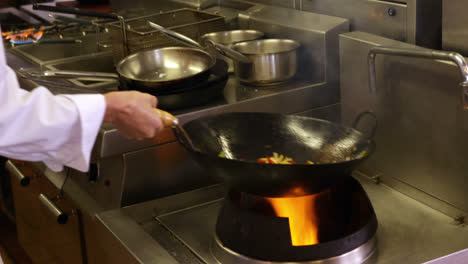 chef tossing vegetables over a large flame