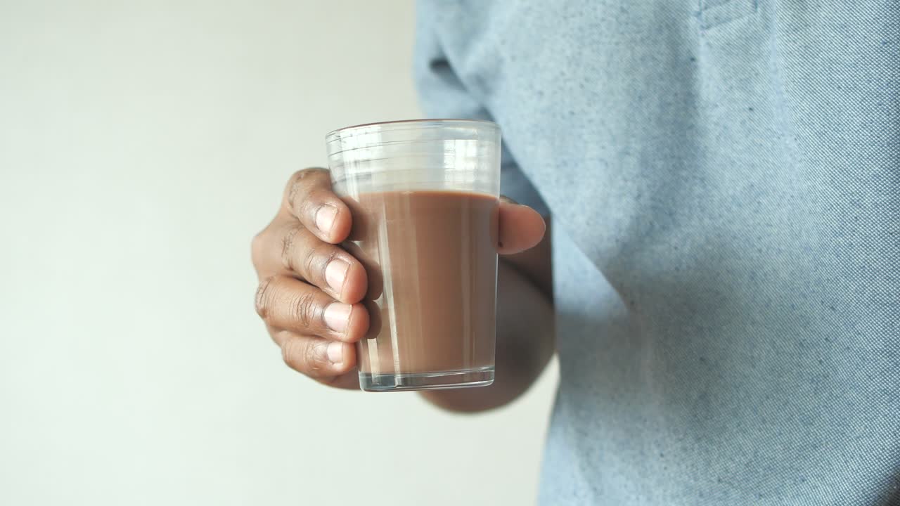 Persona che tiene in mano un bicchiere di latte al cioccolato