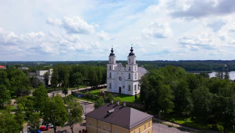 drone view of the central square in zarasai featuring colorful buildings and a white church framed by trees. shot at zarasai, lithuania (zarasai, lietuva)