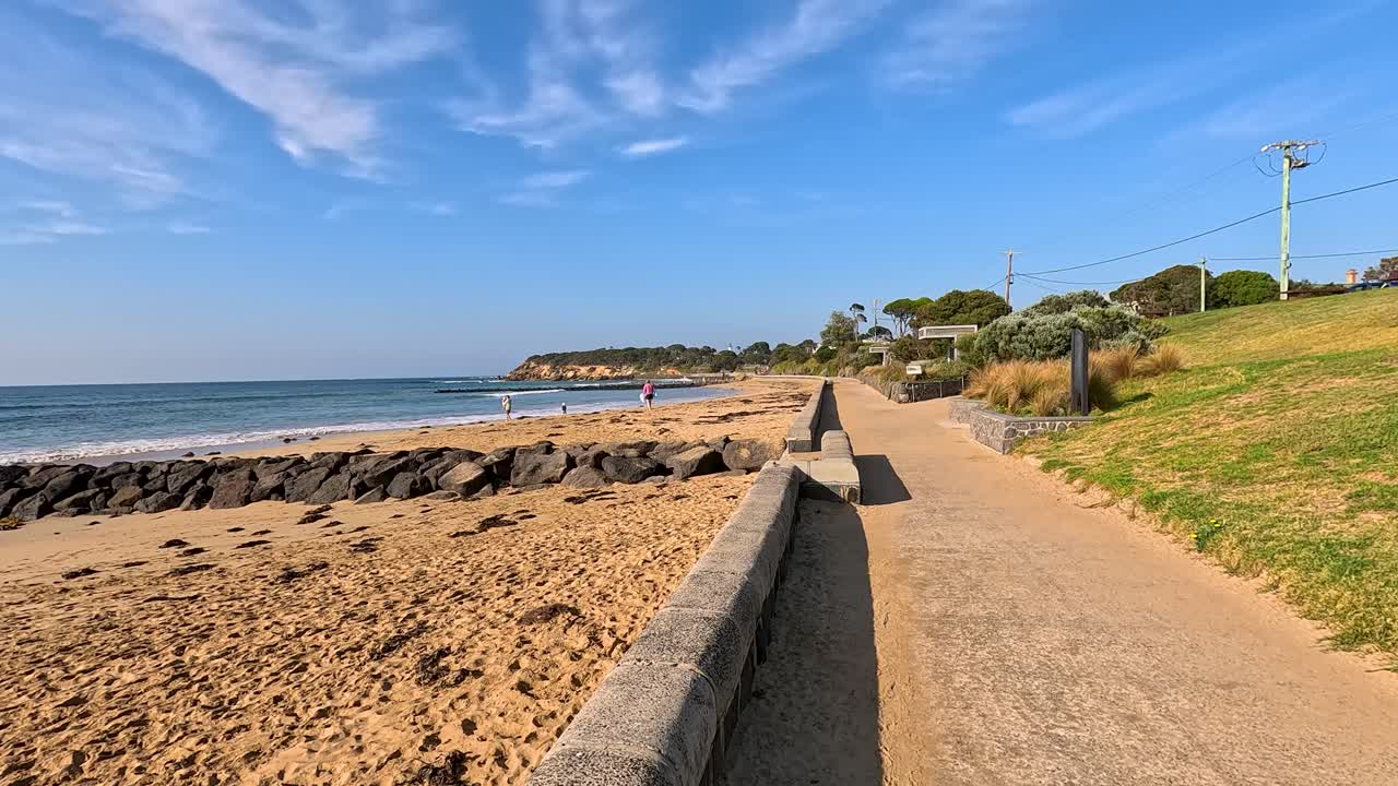 A serene coastal path along Point Lonsdale beach under clear blue skies, showcasing the natural beauty and tranquility of the area