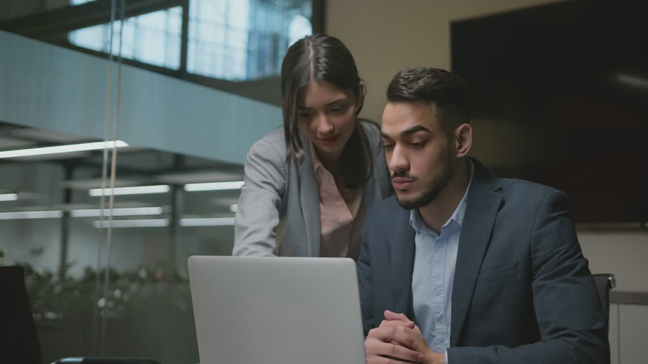 joven empleada explicando el proyecto a su jefe de oriente medio, leyendo análisis de negocios en la computadora portátil en la oficina