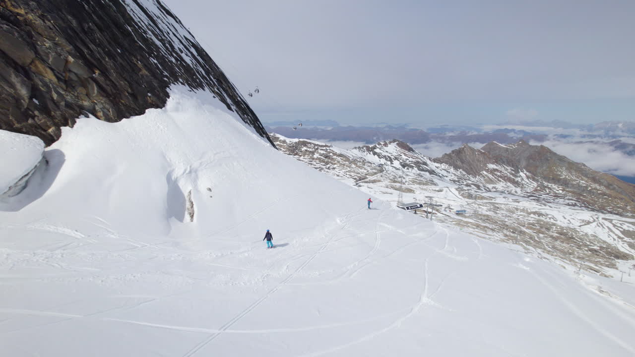 toma aérea de seguimiento de snowboarder acelerando cuesta abajo montañas nevadas a la luz del sol - austria, europa