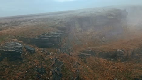 vista aérea de una niebla increíble que se mueve sobre las cimas de los acantilados, colinas doradas nubladas y hermosos acantilados rocosos y páramos