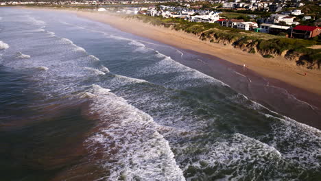 drone tilt-up view of waves crashing onto lappiesbaai sandy beach at sunrise