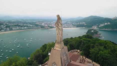 Parallaxe-Der-Luftumlaufbahn-Um-Die-Christusstatue-Von-San-Sebastian-In-Spanien,-Mit-Blick-Auf-Die-Grüne-Bucht-Und-Die-Goldenen-Sandstrände