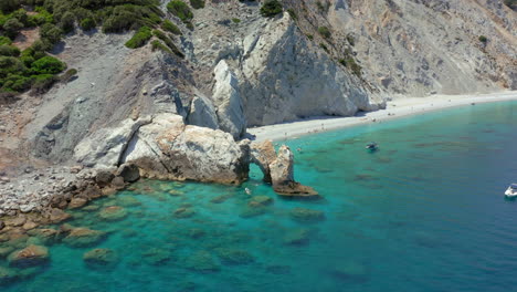 aerial: flying over the limestone arch rock formation in lalaria beach in skiathos island, sporades, greece with turquoise and emerald crystal clear water