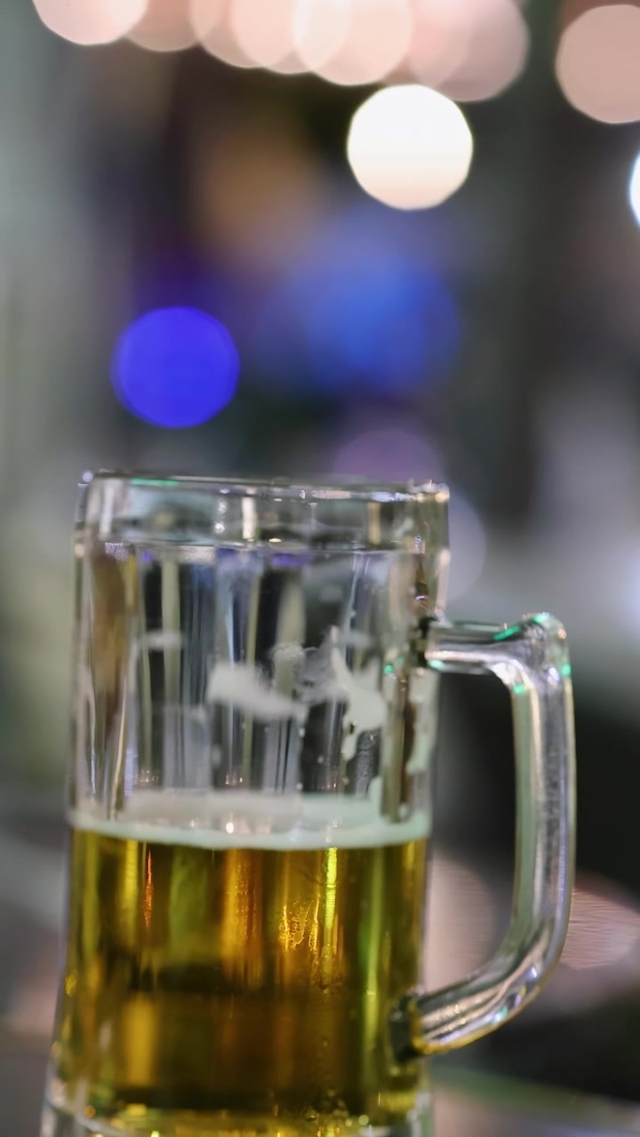 Boccale di birra in vetro su un bancone da bar di notte