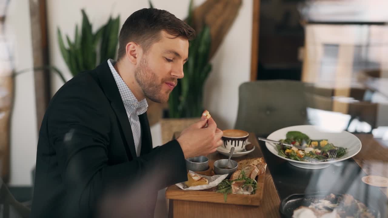 hombre de negocios se come las manos con avidez mientras está sentado en una mesa en un restaurante