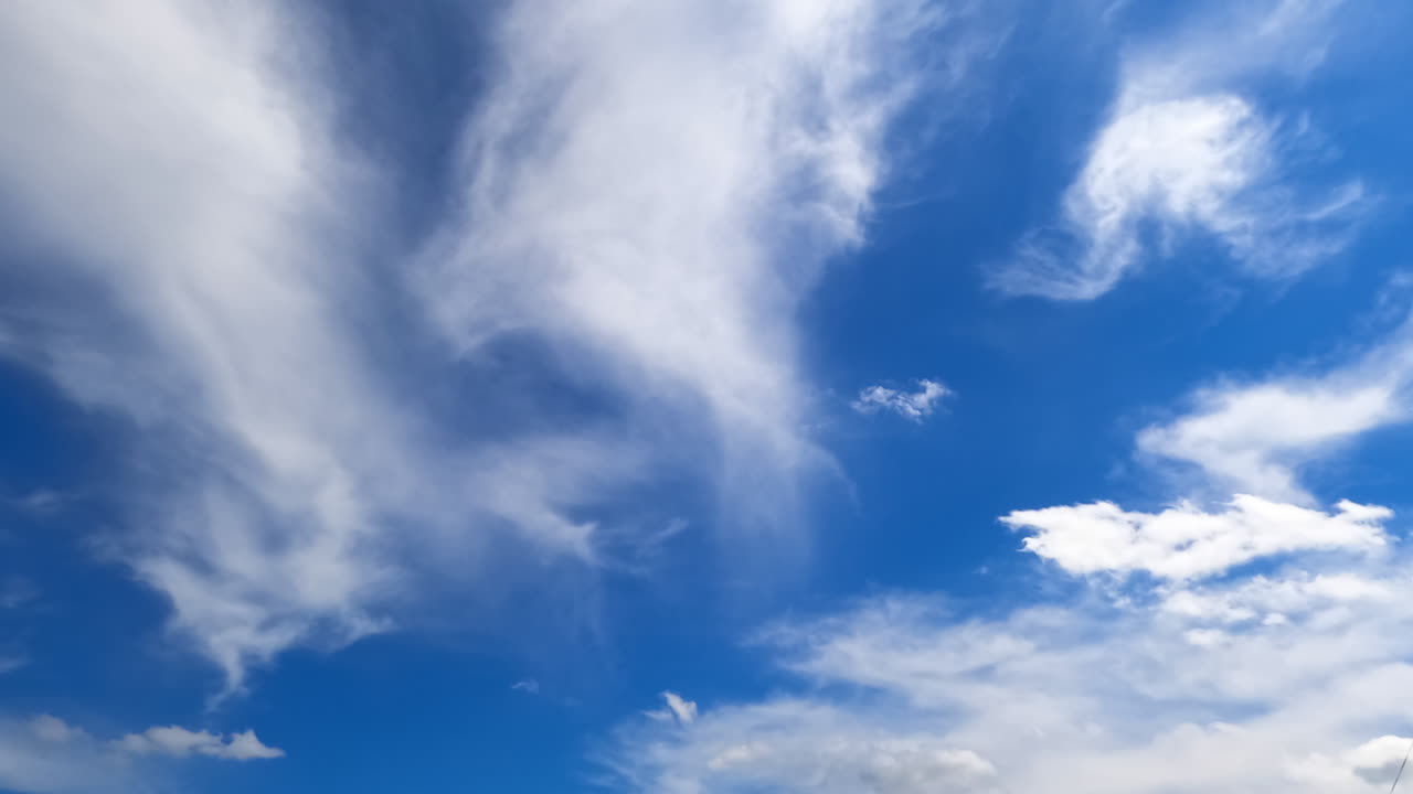 Amazing blue sky with floating fluffy white clouds. Low angle view on the clouds flying above. Timelapse.