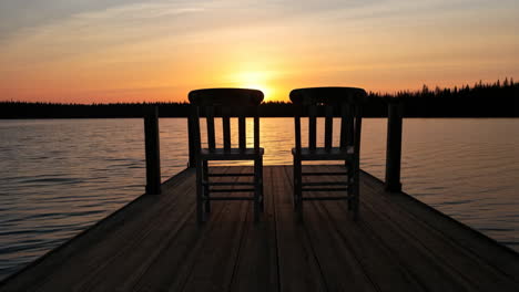 Two chairs on a dock at sunset