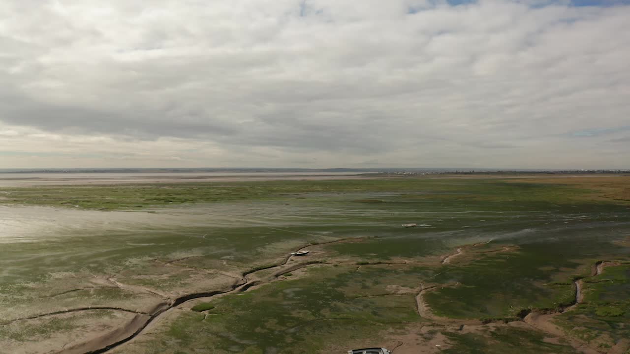 un disparo ascendente desde el suelo a 200 pies revela un barco solitario sobre un pueblo pesquero costero sobre pantanos.