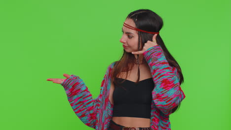 young hippie woman looking at camera doing phone gesture like says hey you call me back conversation