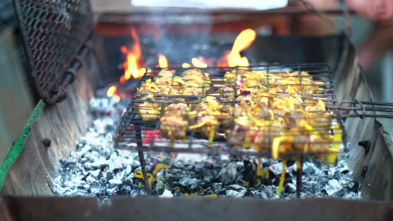 Curried onion lamb skewers on grid being barbecued on coals of wood fire