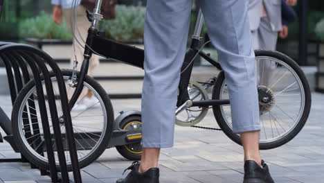 man getting off bicycle on sidewalk at downtown. male legs with bike closeup.