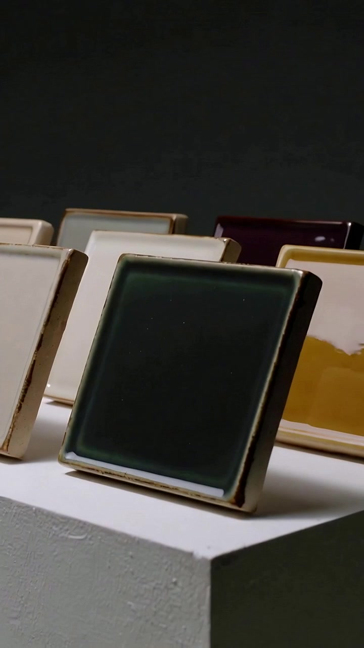 Video verticale: Luce che si sposta, un bagliore che scorre su una piastrella verde con bordo dorato su un supporto, piastrelle sullo sfondo.