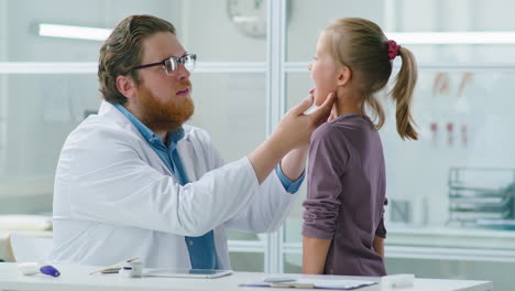 pediatrician examining neck and throat of little girl