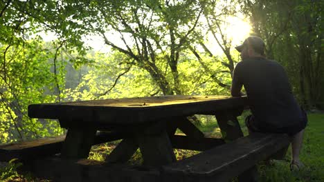 Man-sitting-at-picnic-table-enjoying-the-sunrise