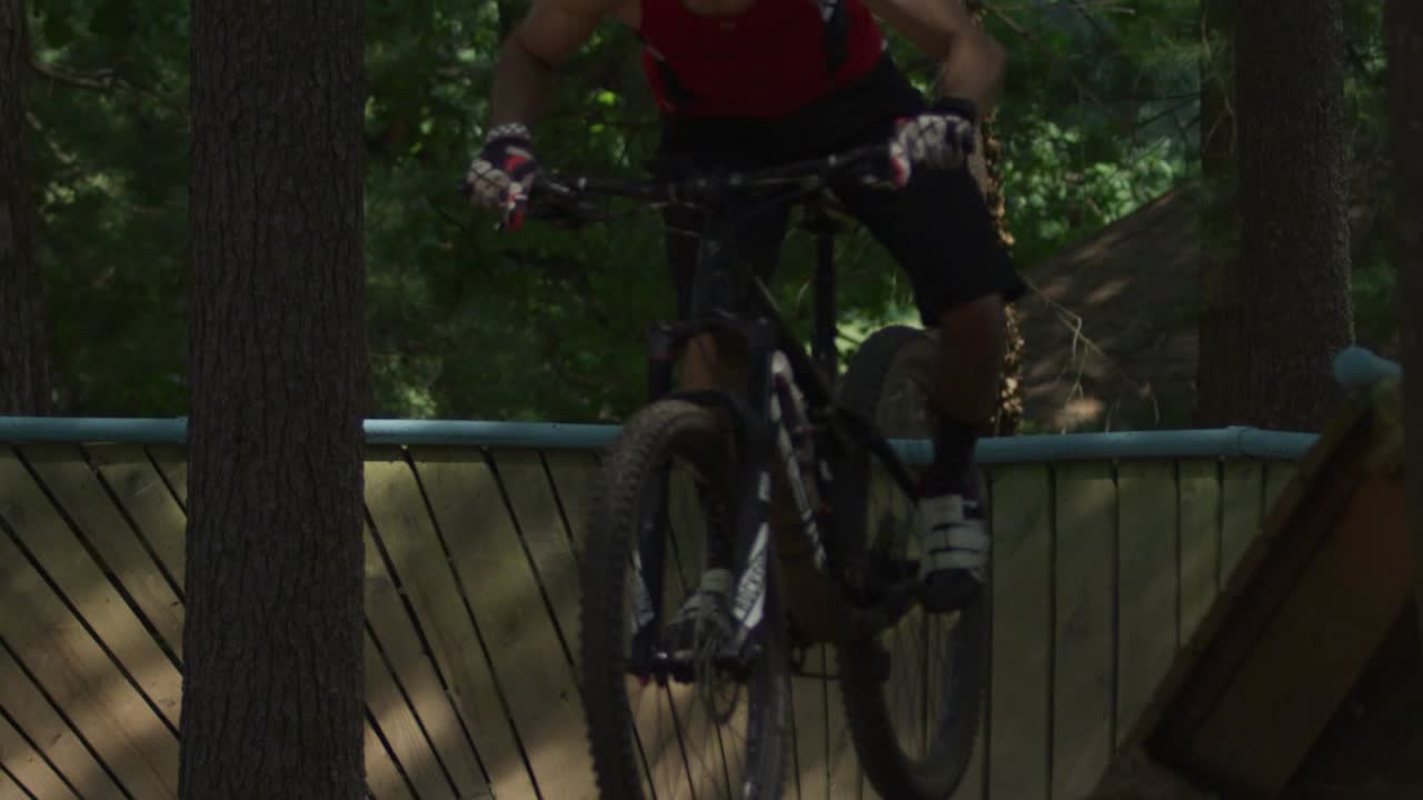 Mountain biker riding a wall turn in the forest, close up, slow motion