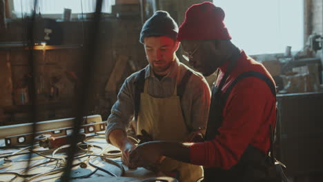 two blacksmiths discussing metal details in workshop