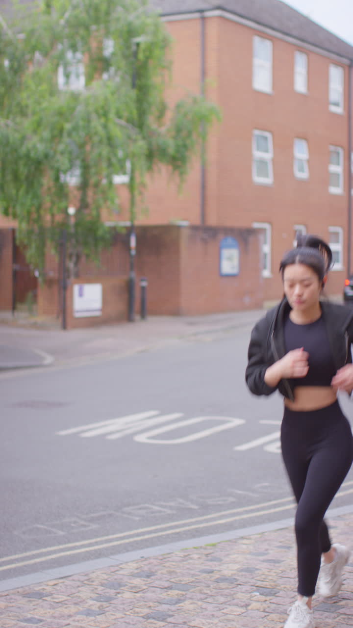 Vertical Video Of Young Woman Exercising Running Along Urban Street Wearing Wireless Earbuds Shot In Real Time