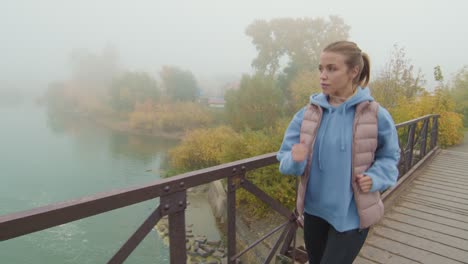 blonde girl with headphones running on a wooden bridge on a cloudy day 1