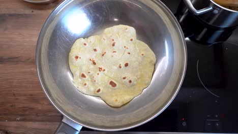 top down view of frying a slice of tortilla dough in a frying pan