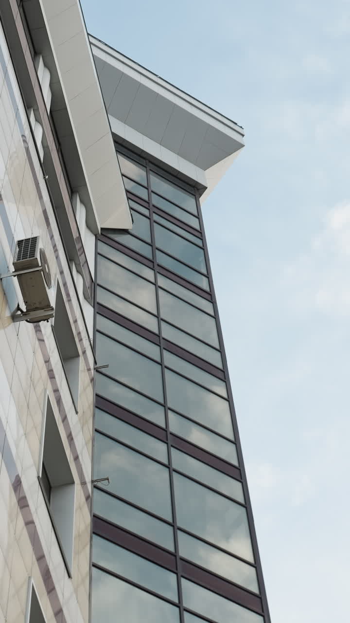 vista lateral cercana de un edificio urbano moderno con una unidad de aire acondicionado montada en la pared, con un diseño elegante de la fachada del edificio y ventanas de vidrio reflectantes
