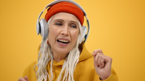 mujer sonriente escuchando música con auriculares en el interior. dama alegre bailando dentro.