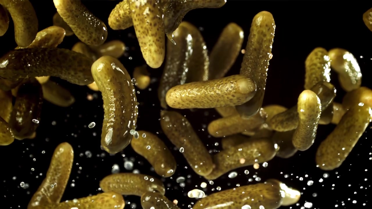 Ralenti de concombres marinés volant avec des éclaboussures d'eau