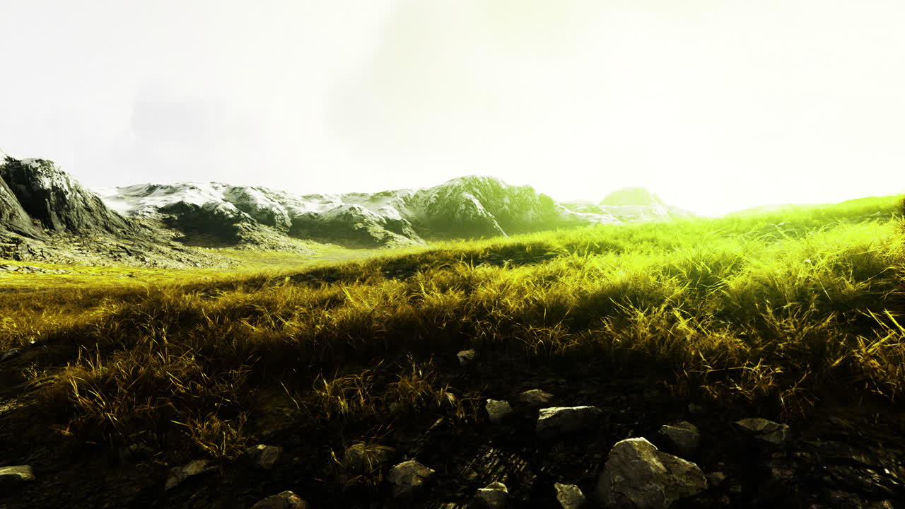 Majestic landscape featuring mountains and lush grass illuminated by sunlight