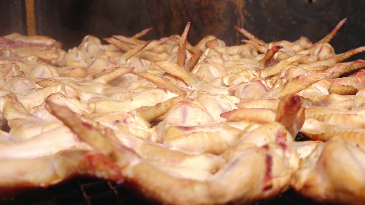 A large batch of golden-brown smoked chicken wings arranged on a grill rack. The wings appear juicy and well-cooked, ideal for barbecue or party servings.