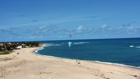 Aerial-drone-shot-of-kite-surfers-pratciting-on-the-tropical-Barra-do-Cunhaú-beach-in-Canguaretama-where-the-large-Curimataú-river-meets-the-sea-in-the-state-of-Rio-Grande-do-Norte,-Brazil