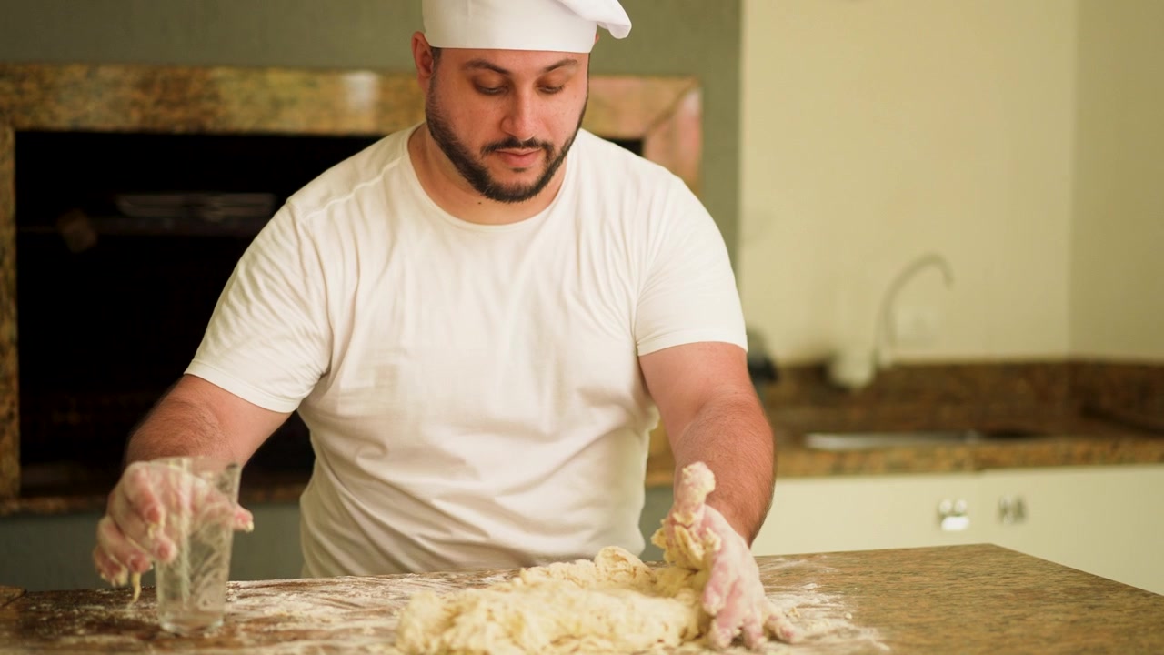 Un momento in cui uno chef versa acqua sulla farina su un piano di lavoro, mostrando l'arte della preparazione della pizza fatta in casa