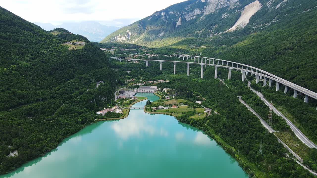 Turquoise Lago Morto lake surrounded by lush mountains, highway bridge viaduct