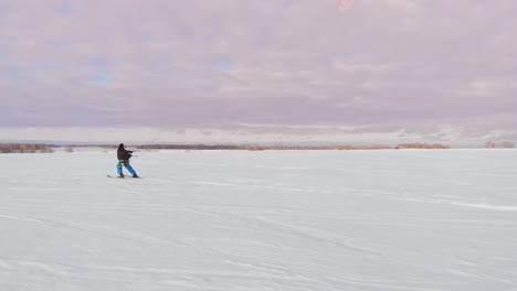 a man is skiing in the snow in a field at sunset. his parachute pulls. kite surfing in the snow..