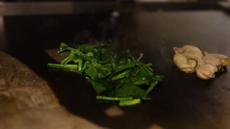 chef fritando espinacas y ostras en un wok