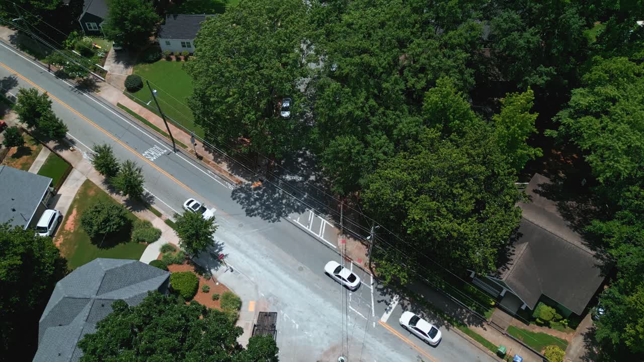 Cars on main street of quiet neighborhood in suburb of Atlanta, Georgia. Sunny summer day with green trees and power poles. Aerial top down shot
