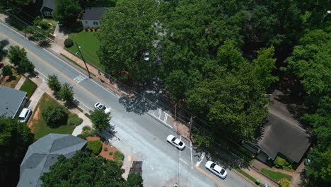 cars on main street of quiet neighborhood in suburb of atlanta, georgia. sunny summer day with green trees and power poles. aerial top down shot