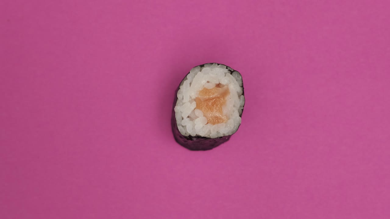 Sushi roll rotating on pink background