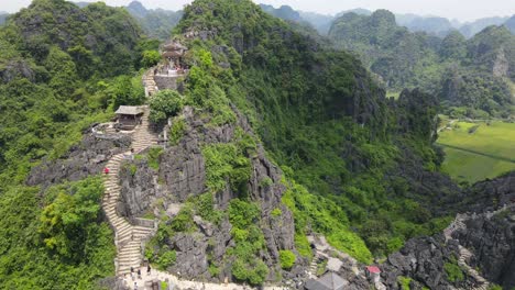 drone shot of rocky mountain with staircases lead to the peak with temple and stone dragon in ninh binh viet nam