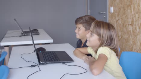 Two classmates sitting at desk with laptop