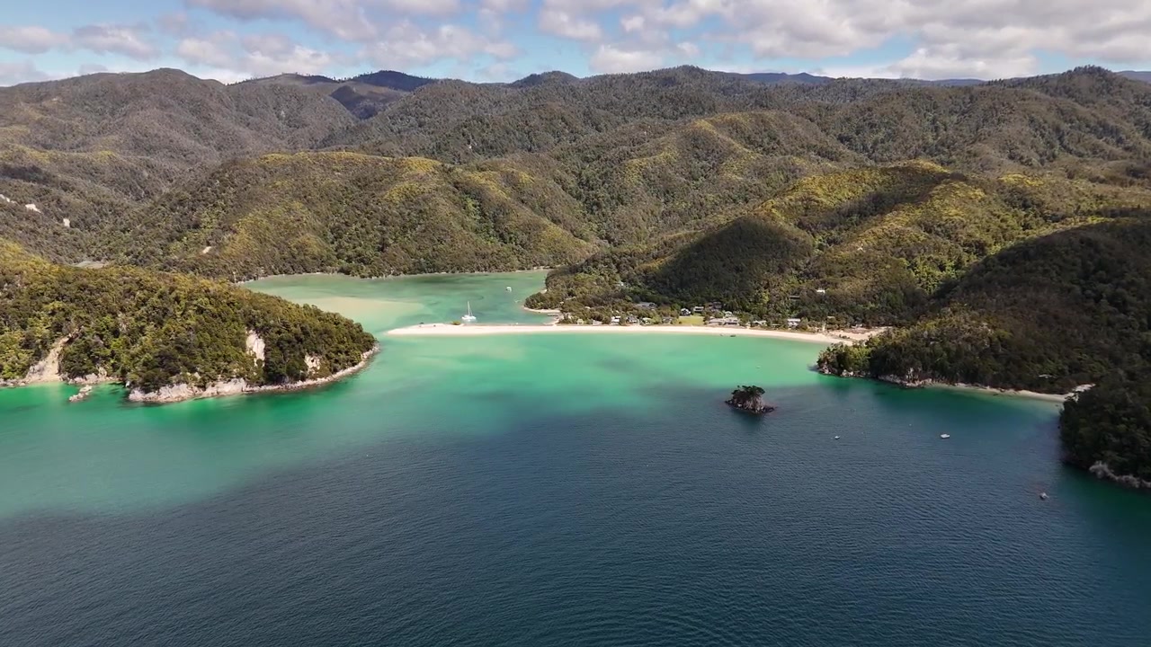 La splendida Baia di Te Pukatea ad Abel Tasman, Nuova Zelanda. La ripresa aerea in 4K cattura acque turchesi incontaminate, spiagge dorate e lussureggianti montagne costiere verdi.