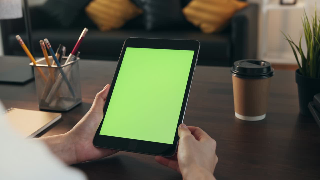 Woman holding digital tablet with green screen and touch device browsing Internet.